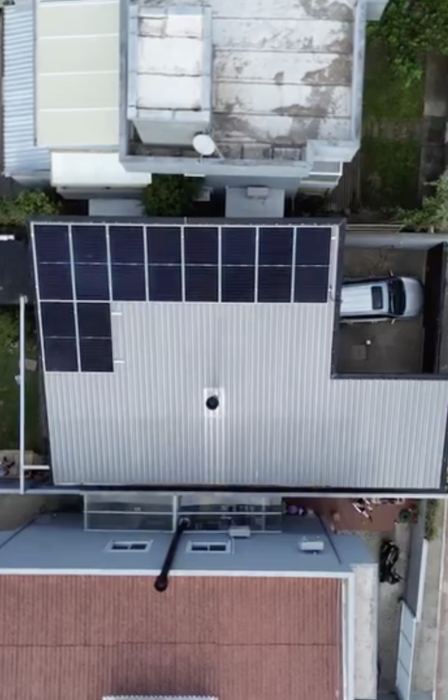 Vista aérea de painéis solares em telhado metálico de residência
